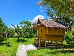a small hut with a grass roof on a field at Tarzan Bamboo hut in Khao Sok National Park