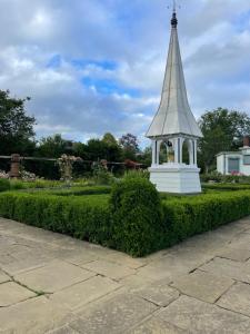 a small tower in a garden with a green hedge at Rushes View Homestay in Market Harborough