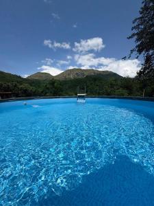 Ein großer Pool mit blauem Wasser und Bergen im Hintergrund in der Unterkunft Palazzo Modafi in Bagni di Lucca