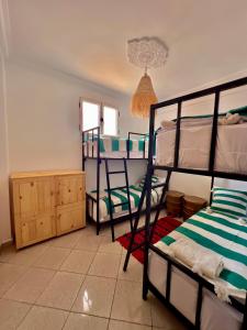 a room with three bunk beds and a mirror at Amzil Surf House in Aourir