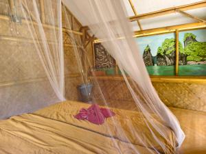 a bed with a mosquito net in a room at Tarzan Bamboo hut in Khao Sok National Park