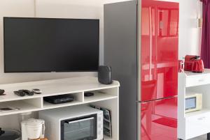 a living room with a tv on a white entertainment center at Charmant studio avec vue sur mer au Moule, 20 m² + terrasse in Le Moule