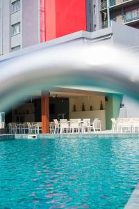 ein Wasserbecken mit weißen Stühlen und Tischen in der Unterkunft GHS Hotel in Brazzaville
