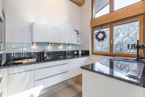 a kitchen with white cabinets and a large window at Chasa Teja by MEIN SAMNAUN - MOUNTAIN HOMES in Samnaun +5 photos