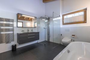 a bathroom with a tub and a toilet and a sink at Chasa Teja by MEIN SAMNAUN - MOUNTAIN HOMES in Samnaun