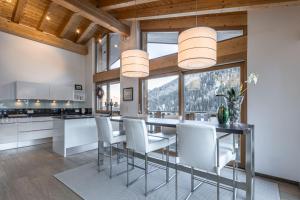 a kitchen with a dining table and white chairs at Chasa Teja by MEIN SAMNAUN - MOUNTAIN HOMES in Samnaun