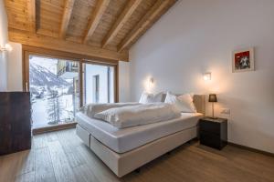 a bedroom with a bed and a large window at Chasa Teja by MEIN SAMNAUN - MOUNTAIN HOMES in Samnaun