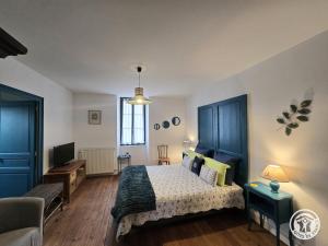 a bedroom with a bed and a couch and a tv at Chambres d'hôtes Ecole Buissonnière en Dordogne in Le Buisson de Cadouin