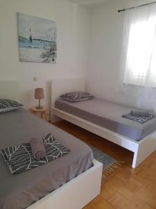 a bedroom with two beds and a window at Apartman Meli in Rab