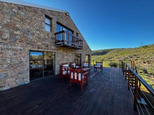 a wooden deck with chairs and a balcony on a building at Shama Private Group Lodge in Steytlerville