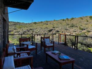 a deck with chairs and tables with a hill in the background at Shama Private Group Lodge in Steytlerville +71 photos