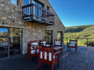 a deck with chairs and a balcony on a building at Shama Private Group Lodge in Steytlerville