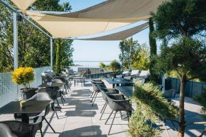 an outdoor patio with tables and chairs and trees at Port étterem&panzió in Balatonmáriafürdő