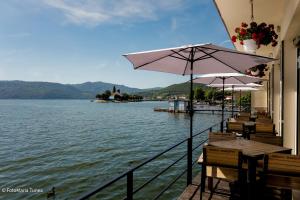 a row of tables with umbrellas next to a lake at Pensiunea Damiro in Orşova +30 photos