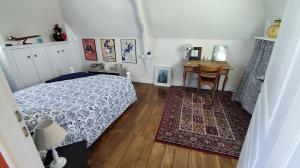 a bedroom with a bed and a table and a desk at Ty Maen - Étage avec chambre, coin salon, toilettes et salle de bain in Erdeven