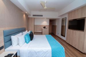 a bedroom with a bed with a blue headboard and a television at Metro park inn in Coimbatore