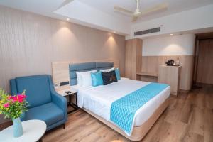 a bedroom with a bed and a blue chair at Metro park inn in Coimbatore +23 photos