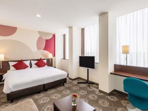 a hotel room with a bed and a flat screen tv at Webers Hotel im Ruhrturm Essen by Accor in Essen