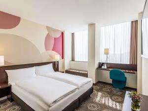 a hotel room with a bed and a chair at Webers Hotel im Ruhrturm Essen by Accor in Essen +99 photos