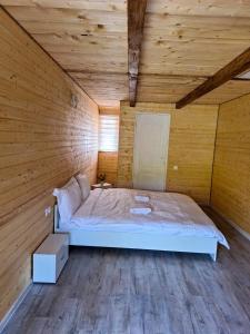 a bedroom with a large bed in a wooden room at Butoiașele Montesanto - Explora y Alegrate in Copalnic Mănăştur