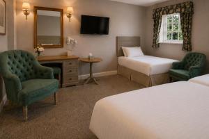 a hotel room with two beds and a desk and chairs at Marston Farm Hotel in Sutton Coldfield