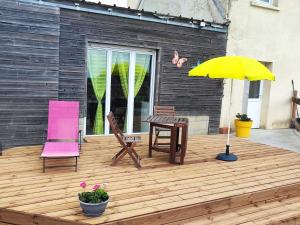 a deck with two chairs and a table and an umbrella at Studio des Mèzerets in La Chapelle-Engerbold