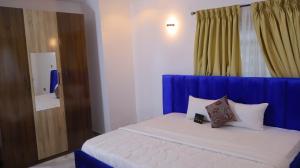 a bed with a blue headboard in a room at Wakanda Apartment in Mama