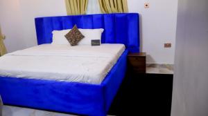a bed with a blue head board in a room at Wakanda Apartment in Mama