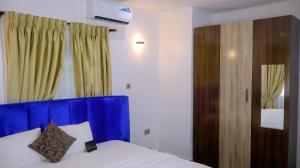 a bedroom with a bed with a blue head board at Wakanda Apartment in Mama
