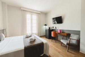 a bedroom with a bed and a desk and a television at Alcazaba Premium Hotel in Málaga