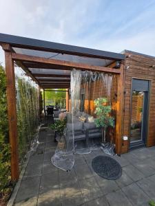 a wooden pergola with a couch on a patio at Baltic Lark Gąski domek 30m2, taras zadaszony 27m2 ogródek klimatyzacja in Gąski