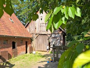 a large wooden barn with a little girl standing next to it at Lieblingsnest in Bad Fallingbostel