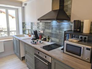 a kitchen with a stove and a microwave at Le Céleste T2 cosy en hypercentre de Gap in Gap