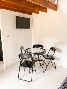 a glass table and four chairs in a room at Charmant studio avec terrasse à Chenou, 20 m² in Chenou +8 photos