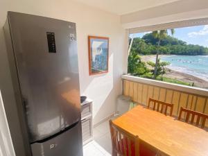 a kitchen with a refrigerator and a table and a window at Studio confortable avec vue sur la mer in Le Gosier