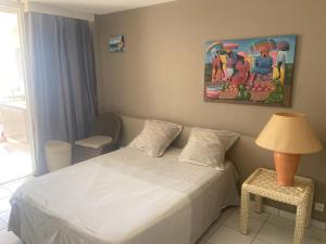 a bedroom with a bed and a table with a lamp at Studio confortable avec vue sur la mer in Le Gosier