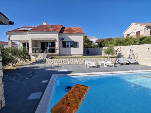 a swimming pool in front of a house at Villa Pauliana in Povljana