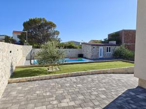 a house with a courtyard with a tree in a yard at Villa Pauliana in Povljana