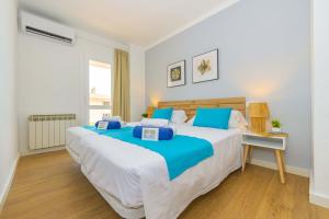 a bedroom with a large white bed with blue pillows at Seafront Cala Ratjada Apartment in Cala Ratjada