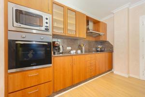 a kitchen with wooden cabinets and a microwave at Seafront Cala Ratjada Apartment in Cala Ratjada