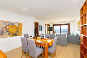 a dining room with a table and chairs and a couch at Seafront Cala Ratjada Apartment in Cala Ratjada