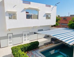 a white house with a swimming pool in front of it at Charming apartment in M'bour + 100 m² + pool in Mbour