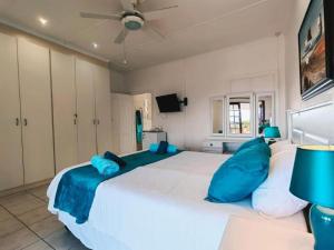 a bedroom with a large white bed with blue pillows at Aviators Paradise Guest House in Mossel Bay