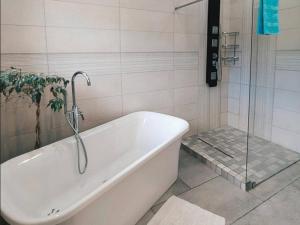 a bath tub in a bathroom with a shower at Aviators Paradise Guest House in Mossel Bay +35 photos