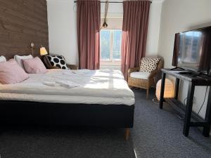 a bedroom with a bed and a television and a chair at Bondasgården in Lima