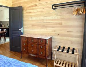 a bedroom with a wooden wall with a dresser and a chair at Emmanon - Appartement in La Coquille