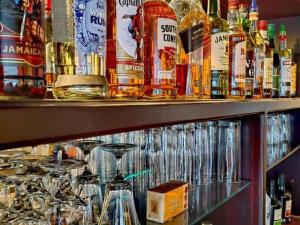a shelf filled with glasses and bottles of alcohol at Aviators Paradise Guest House in Mossel Bay