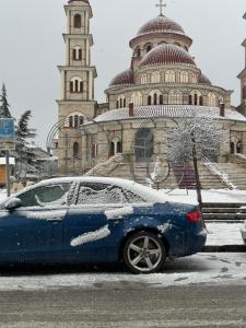 a blue car parked in front of a building at Za Apartment 2 in Korçë +5 photos