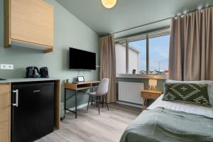 a hotel room with a bed and a desk with a television at ASKA Hraun in Hafnarfjörður