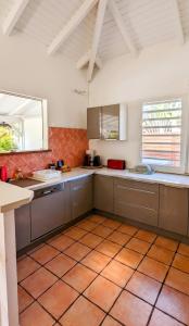a large kitchen with white cabinets and orange tile floors at Villa élégante à Saint-François + Piscine privée in Saint-François